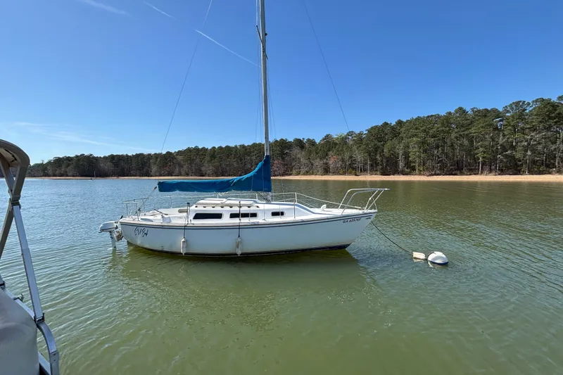Slide: The Image of 1983 Catalina 25 sailboat anchored on a calm lake with forested shoreline. - 34