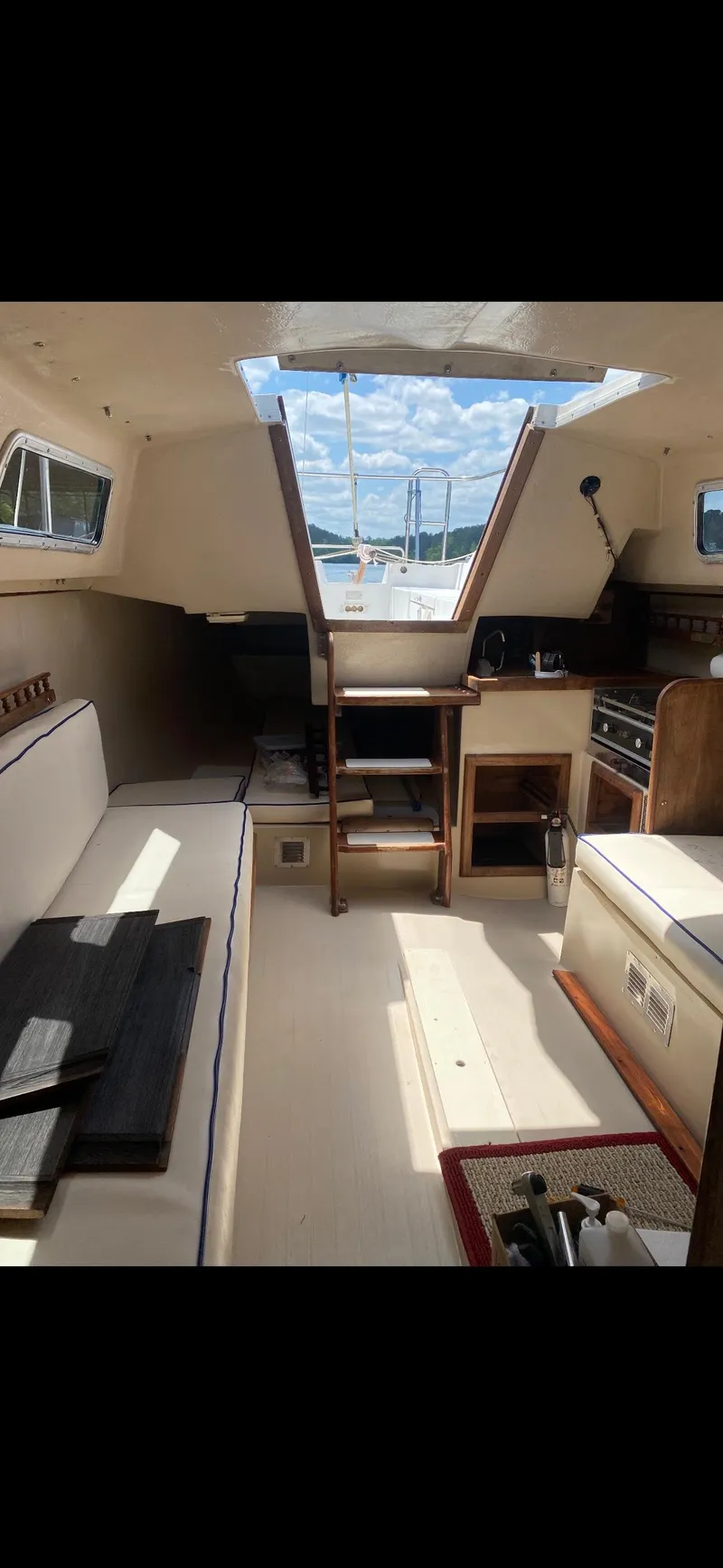Slide: The Image of Interior of a 1983 Catalina 25 sailboat with seating, kitchen, and open hatch. - 6