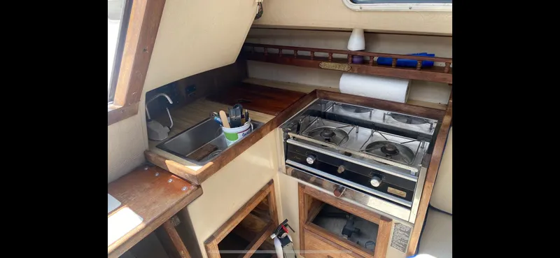 Slide: The Image of Compact kitchen area in a 1983 Catalina 25 sailboat, featuring a stove and sink. - 8