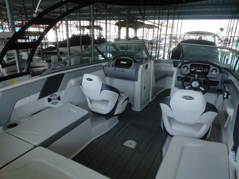 Slide: The Image of 2020 Chaparral 23 SSi boat interior with modern seating and dashboard in a marina. - 13
