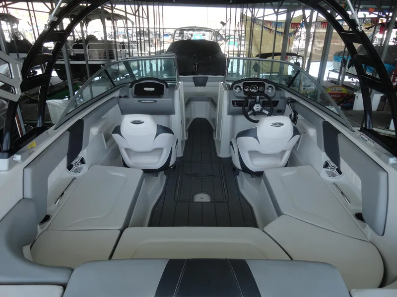 Slide: The Image of 2020 Chaparral 23 SSi boat interior with seating and steering wheel in a marina. - 6