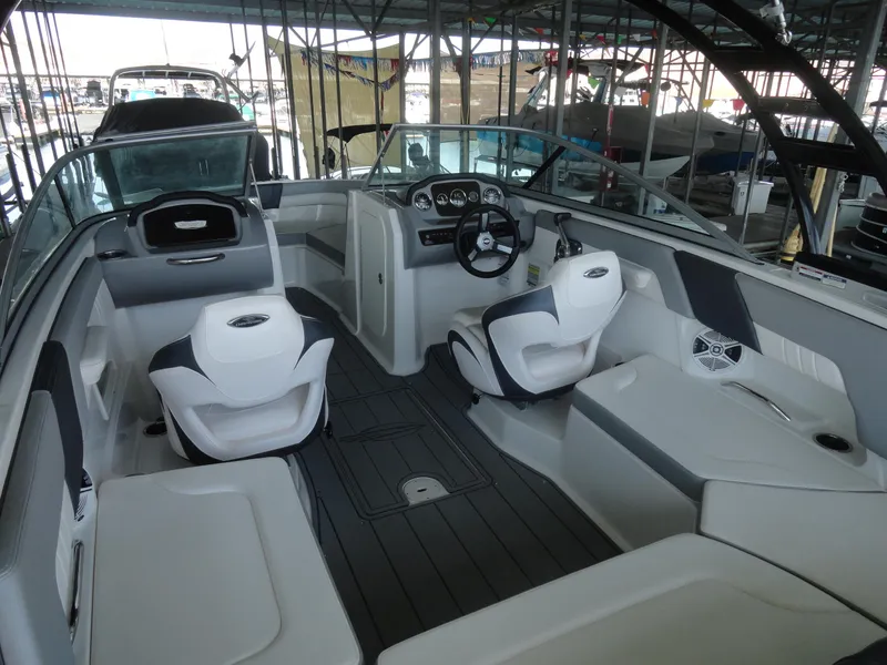 Slide: The Image of 2020 Chaparral 23 SSi boat interior with modern seating and dashboard in a marina. - 7