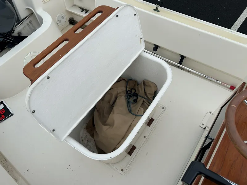 Slide: The Image of Open storage compartment on 2014 Nantucket Boat Works 17 Skiff, containing a tarp and rope. - 11