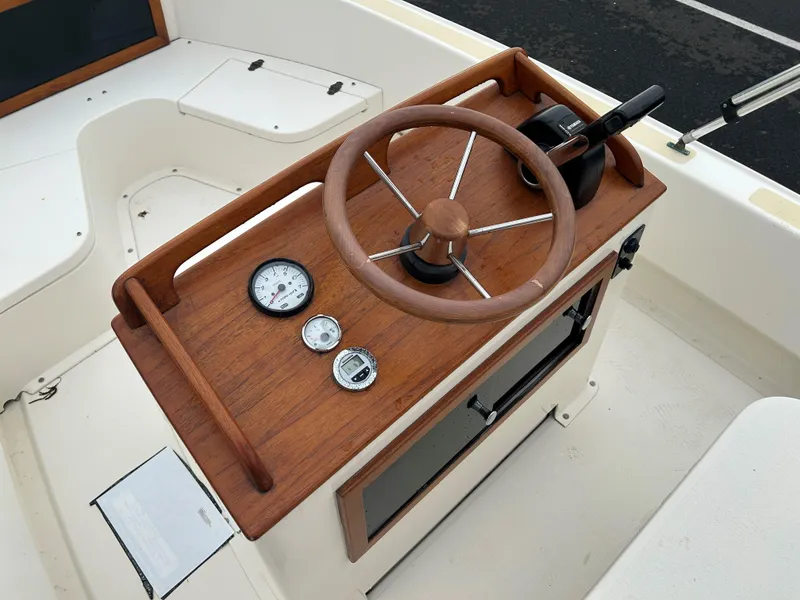 Slide: The Image of Wooden steering console of a 2014 Nantucket Boat Works 17 Skiff, featuring gauges and controls. - 12