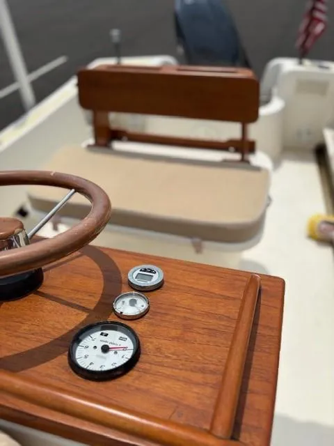 Slide: The Image of 2014 Nantucket Boat Works 17 Skiff interior with wooden dashboard and steering wheel. - 17