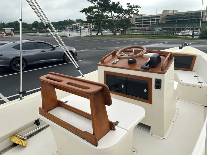 Slide: The Image of 2014 Nantucket Boat Works 17 Skiff with wooden helm, parked near waterfront. - 9