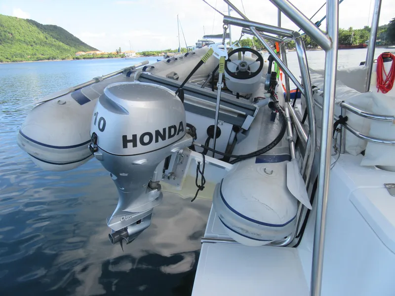 Slide: The Image of Inflatable boat with Honda outboard motor on a Bali 4.1 catamaran, docked by lush green hills. - 17