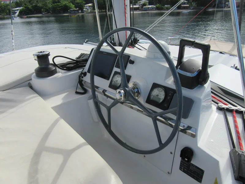 Slide: The Image of Steering wheel and controls of a 2020 Bali 4.1 catamaran, docked by a serene waterfront. - 23