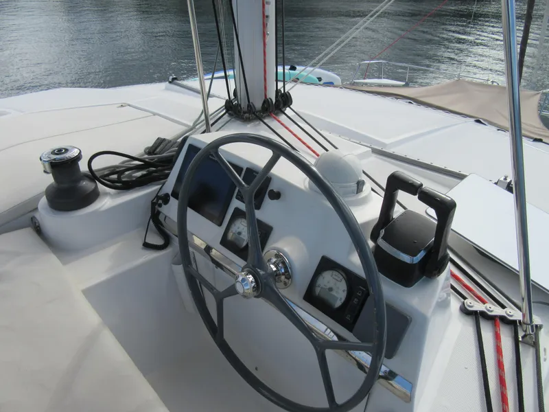 Slide: The Image of Steering wheel and controls of a 2020 Bali 4.1 catamaran on calm water. - 26