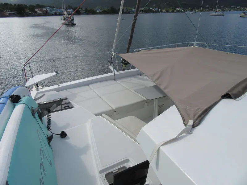 Slide: The Image of Bali 4.1 catamaran deck with sunshade, anchored in a serene bay, 2020 model. - 41