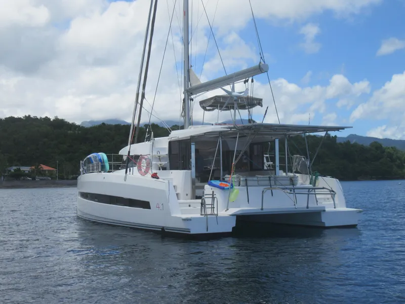 Slide: The Image of 2020 Bali 4.1 catamaran anchored on calm water with lush green hills in background. - 6