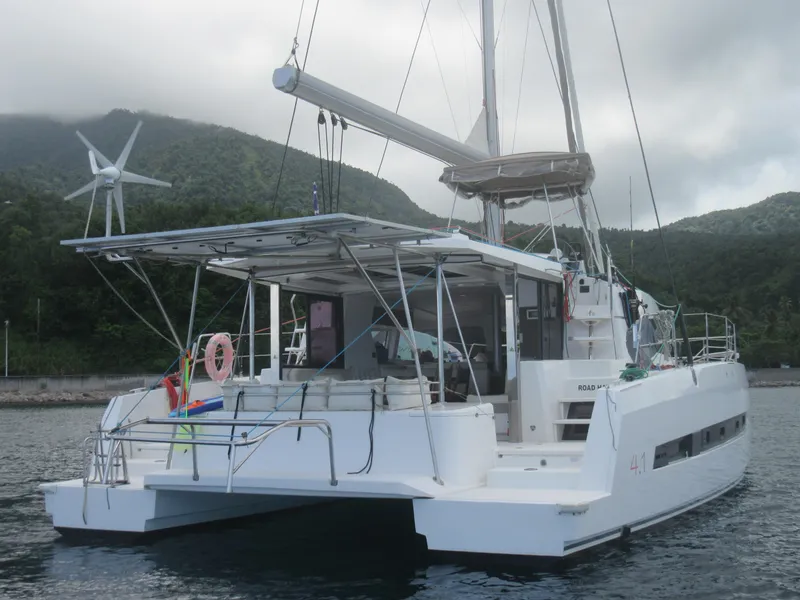 Slide: The Image of 2020 Bali 4.1 catamaran docked near lush green mountains, featuring a wind turbine. - 8