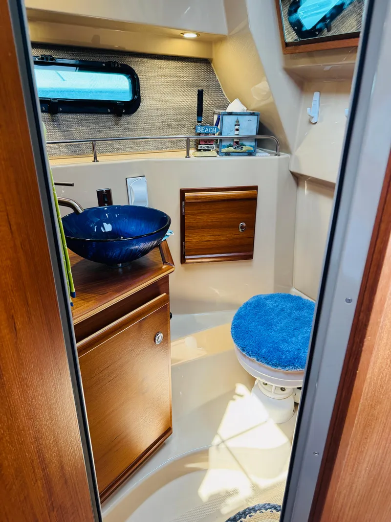 Slide: The Image of 2018 Ranger Tugs R-27 boat bathroom with blue sink and wooden cabinetry. - 13