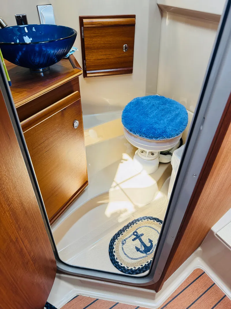 Slide: The Image of 2018 Ranger Tugs R-27 bathroom with blue sink, wooden cabinets, and nautical-themed decor. - 14