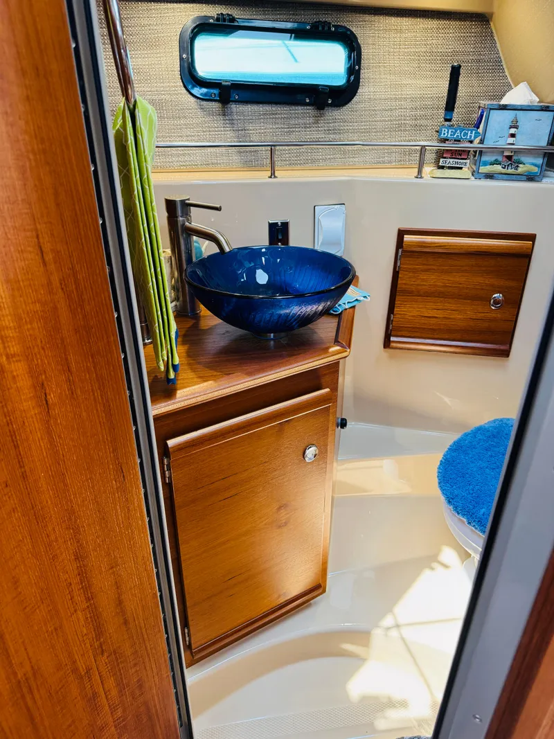 Slide: The Image of 2018 Ranger Tugs R-27 bathroom with wooden cabinetry and blue glass sink. - 16