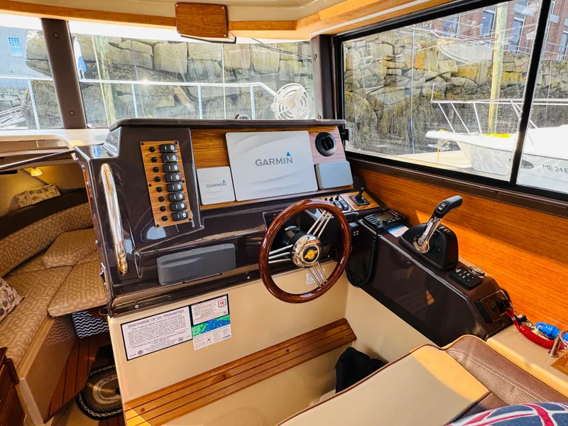 Slide: The Image of 2018 Ranger Tugs R-27 helm with Garmin navigation, wood accents, and comfortable seating. - 18