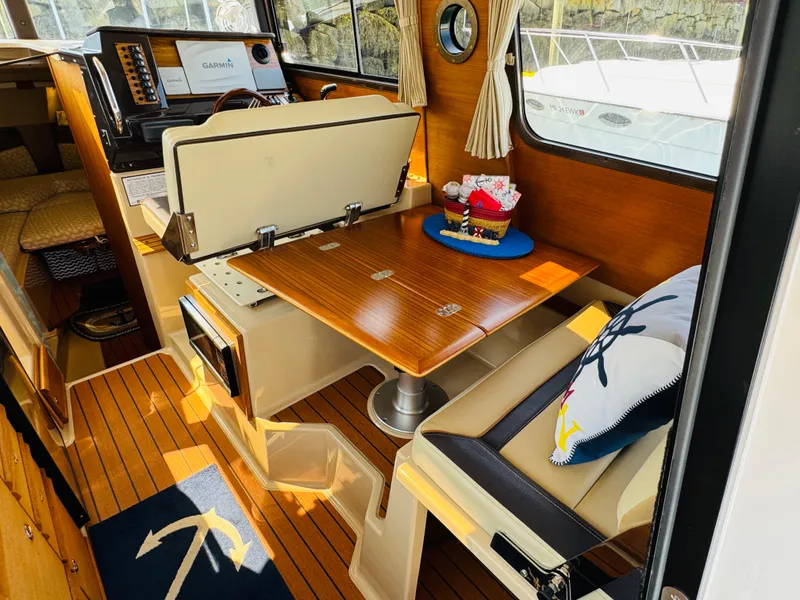 Slide: The Image of 2018 Ranger Tugs R-27 interior with wooden table, nautical decor, and Garmin navigation system. - 2