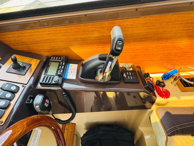 Slide: The Image of 2018 Ranger Tugs R-27 helm with controls, radio, and joystick on wooden dashboard. - 20