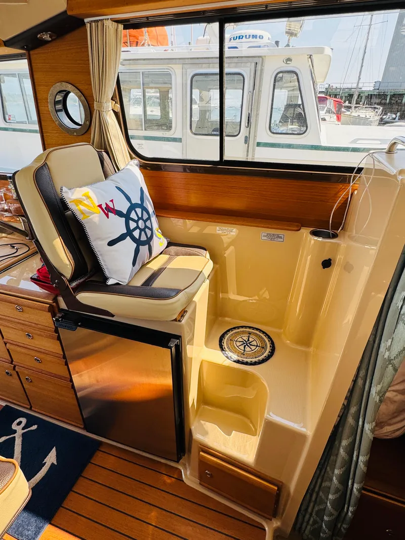 Slide: The Image of 2018 Ranger Tugs R-27 interior with helm seat, nautical decor, and wood accents. - 24