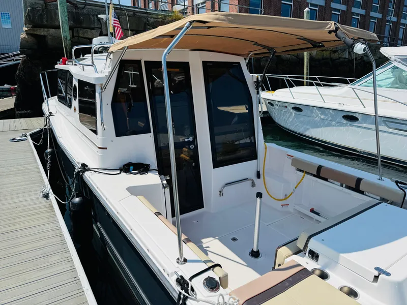 Slide: The Image of 2018 Ranger Tugs R-27 boat docked, featuring a covered cockpit and sleek design. - 25
