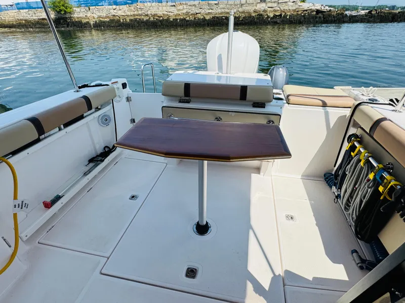Slide: The Image of 2018 Ranger Tugs R-27 boat deck with seating and table, docked by the water. - 28