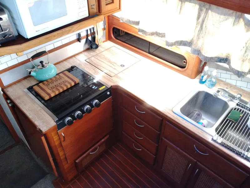 Slide: The Image of 1986 Bayliner 3870 Motoryacht kitchen with stove, sink, and wooden cabinetry. - 16