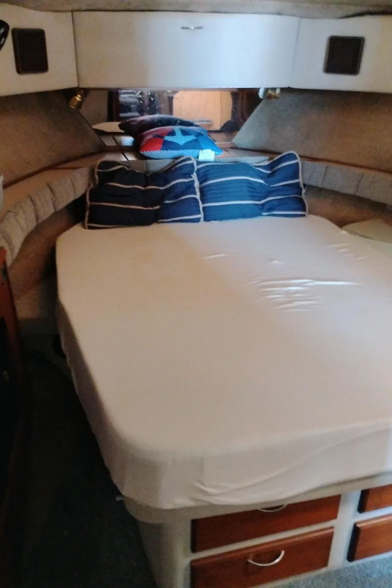 Slide: The Image of 1986 Bayliner 3870 Motoryacht bedroom with bed, blue-striped pillows, and storage drawers. - 22