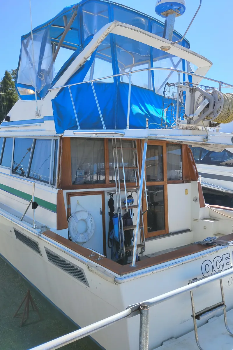 Slide: The Image of 1986 Bayliner 3870 Motoryacht with blue canopy, docked at marina. - 3