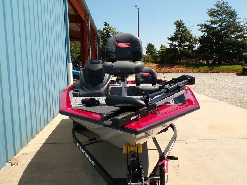 Slide: The Image of 2025 Tracker Pro Team 175 TF® boat, red and gray, parked outdoors near a blue building. - 3