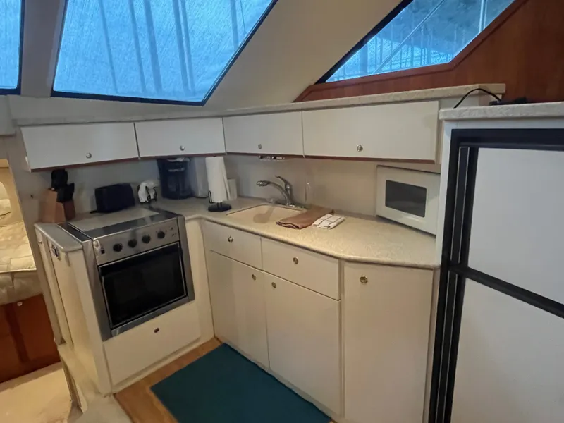 Slide: The Image of 1999 Silverton 392 Aft Cabin kitchen with stove, sink, and microwave under skylight. - 29