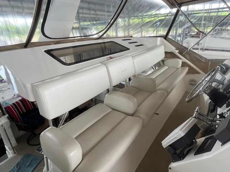 Slide: The Image of 1999 Silverton 392 Aft Cabin helm with white seating and steering controls. - 9