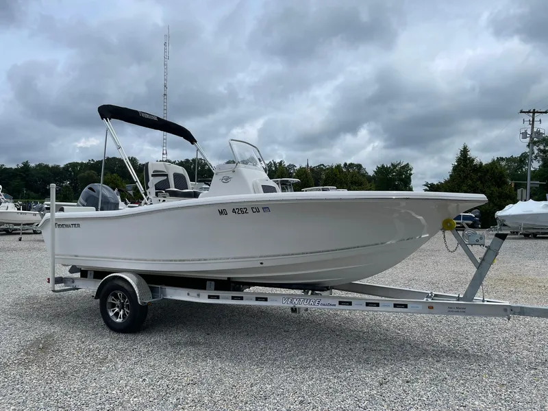 The Image of 2024 Tidewater 198 CC Adventure boat on trailer, parked outdoors under cloudy sky. - 0