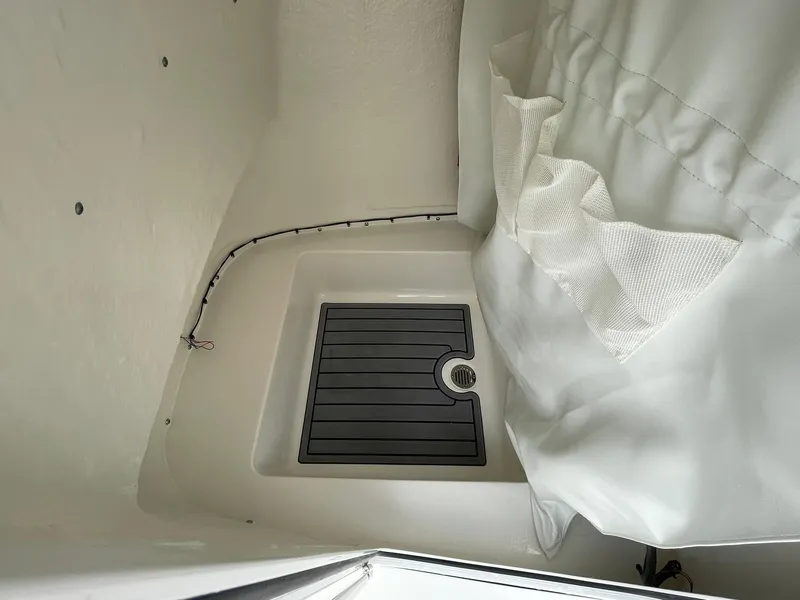 Slide: The Image of 2024 Tidewater 198 CC Adventure boat interior with storage compartment and drain. - 16