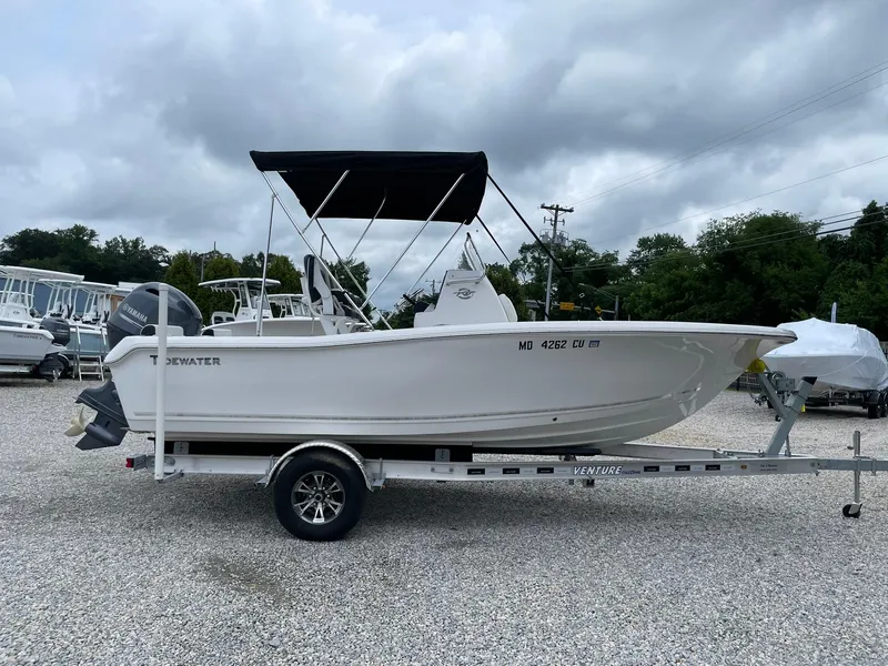 Slide: The Image of 2024 Tidewater 198 CC Adventure boat on trailer, parked outdoors under cloudy sky. - 43