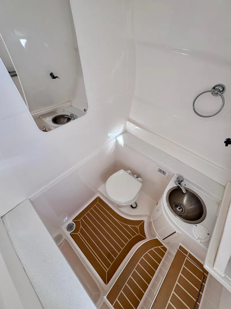 Slide: The Image of 2017 Intrepid 375 FE boat bathroom with toilet, sink, and wooden floor mats. - 6