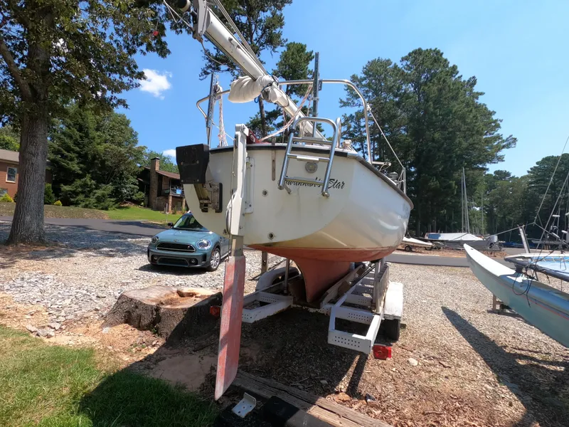 Slide: The Image of 1980 Com-Pac 23 sailboat on trailer, parked outdoors near trees and a car. - 5