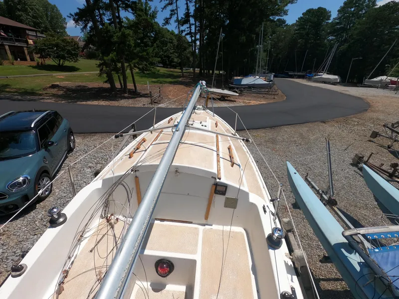 Slide: The Image of 1980 Com-Pac 23 sailboat on land, surrounded by trees and parked cars. - 7