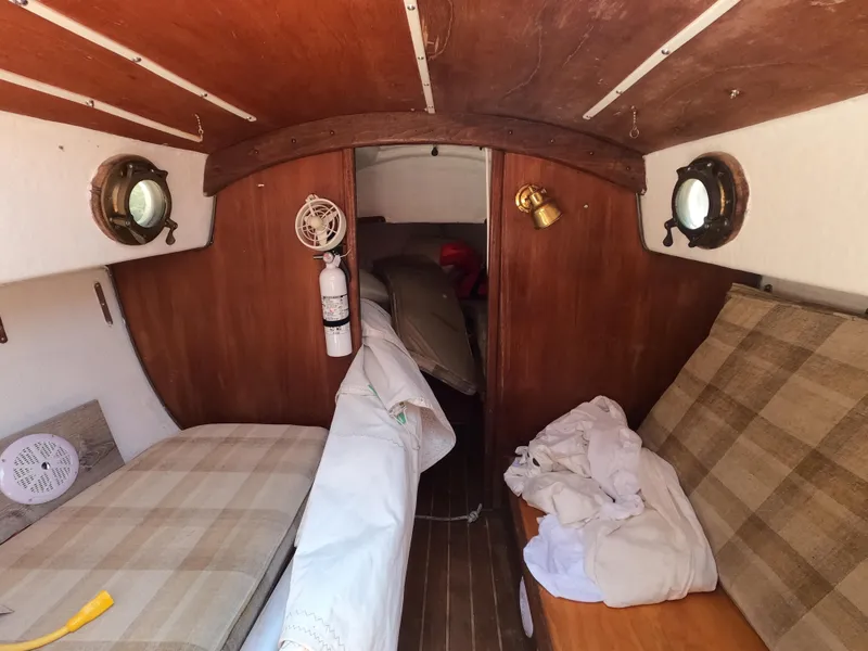 Slide: The Image of Interior of a 1980 Com-Pac 23 sailboat with wooden paneling and cozy seating. - 9