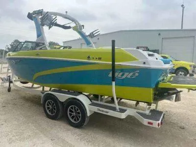 Slide: The Image of 2024 Tigé Z3 boat on trailer, vibrant blue and green design, parked outdoors. - 6