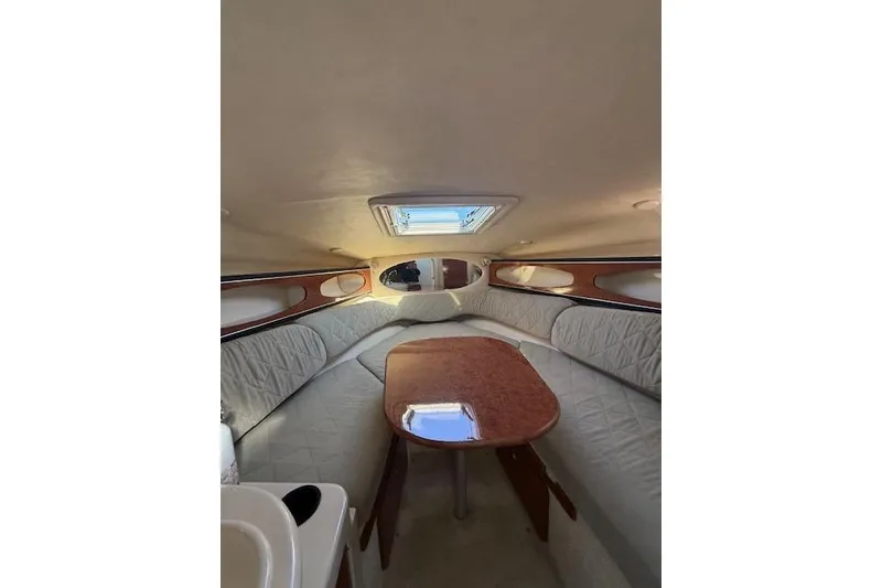 Slide: The Image of Interior of 2003 Sea Ray 260 Sundancer boat with cozy seating and wooden table. - 10