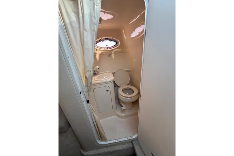 Slide: The Image of 2003 Sea Ray 260 Sundancer boat bathroom with toilet, sink, and porthole window. - 4