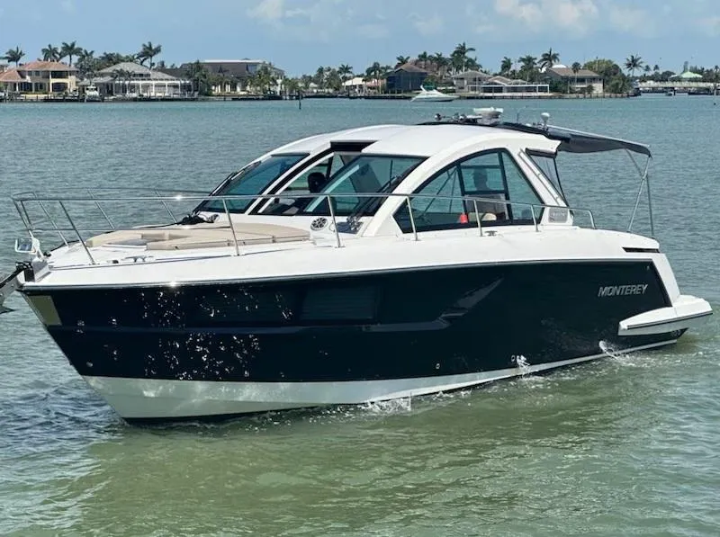 The Image of 2016 Monterey 360 Sport Coupe cruising on calm waters near a coastal neighborhood. - 1