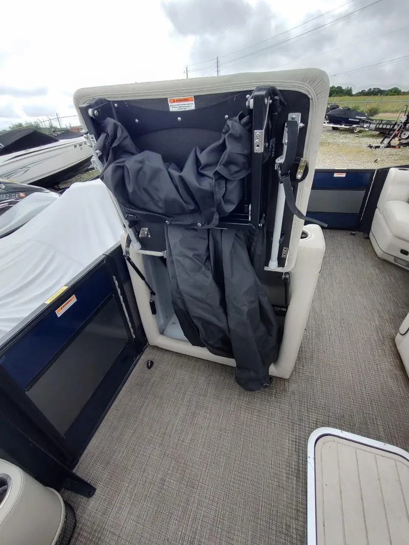 Slide: The Image of 2020 Barletta L23QC boat with open storage compartment and cover, showcasing interior features. - 11