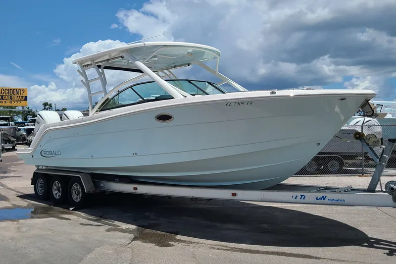 Slide: The Image of 2024 Robalo R317 Dual Console boat on trailer under cloudy sky. - 2