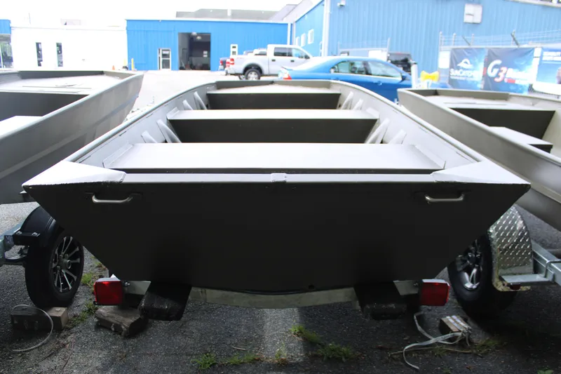 Slide: The Image of 2025 WeldBilt 1548V boat on trailer, parked outside a blue industrial building. - 2