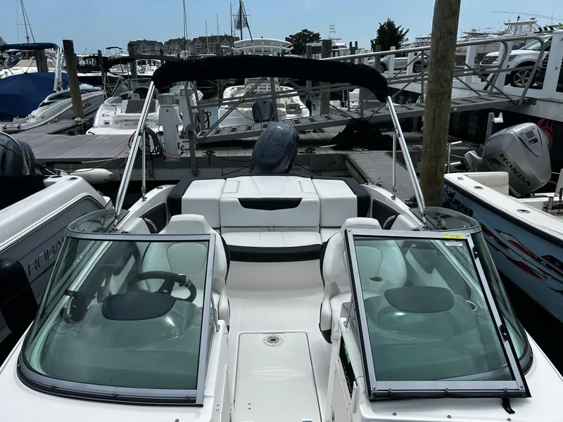 Slide: The Image of 2018 Chaparral 21 H2O Sport OB boat docked at marina, featuring sleek design and spacious seating. - 18