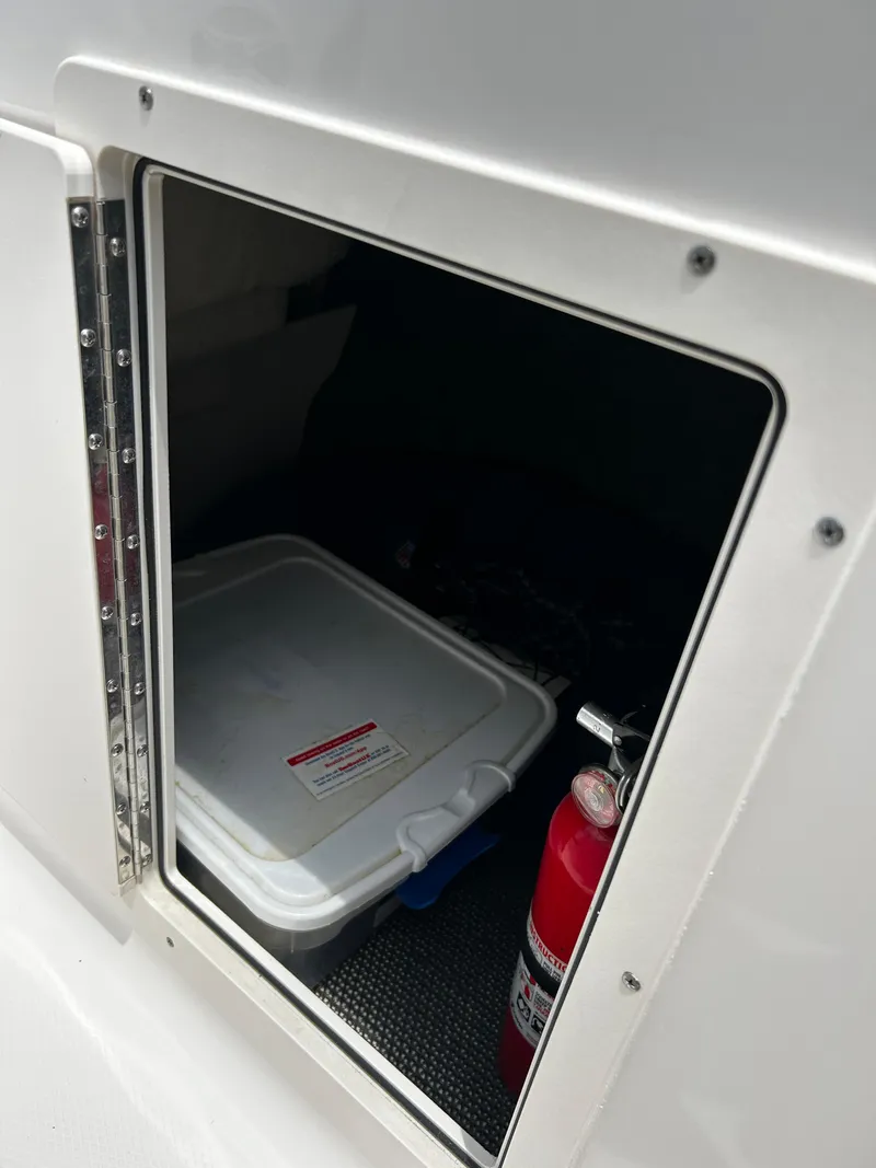 Slide: The Image of Storage compartment in 2018 Chaparral 21 H2O Sport OB with fire extinguisher and container. - 28