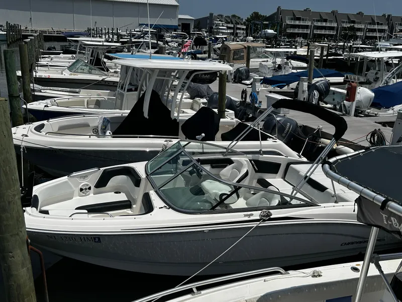 Slide: The Image of 2018 Chaparral 21 H2O Sport OB boat docked at a marina with other vessels. - 9