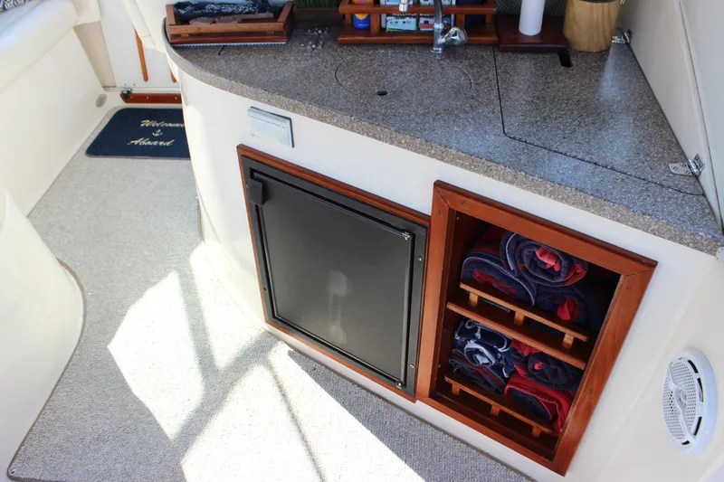 Slide: The Image of 2004 Rinker 342 Express Cruiser interior with countertop, mini fridge, and towel storage. - 10