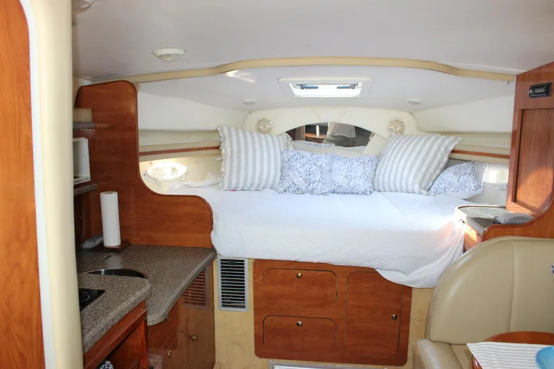 Slide: The Image of 2004 Rinker 342 Express Cruiser cabin interior with bed, pillows, and kitchenette. - 17